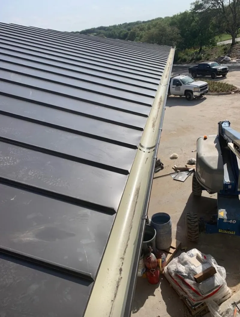 Standing seam panel and gutter detail on a metal roofing jobsite in Whitehall
